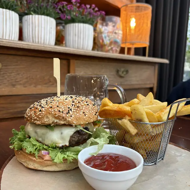 Burger z sałatą i pomidorem, grube fryty i ketchup na drewnianej desce