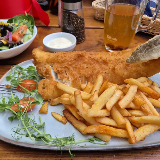 Smażony filet z dorsza z frytkami, surówką i sosem na niebieskim talerzu